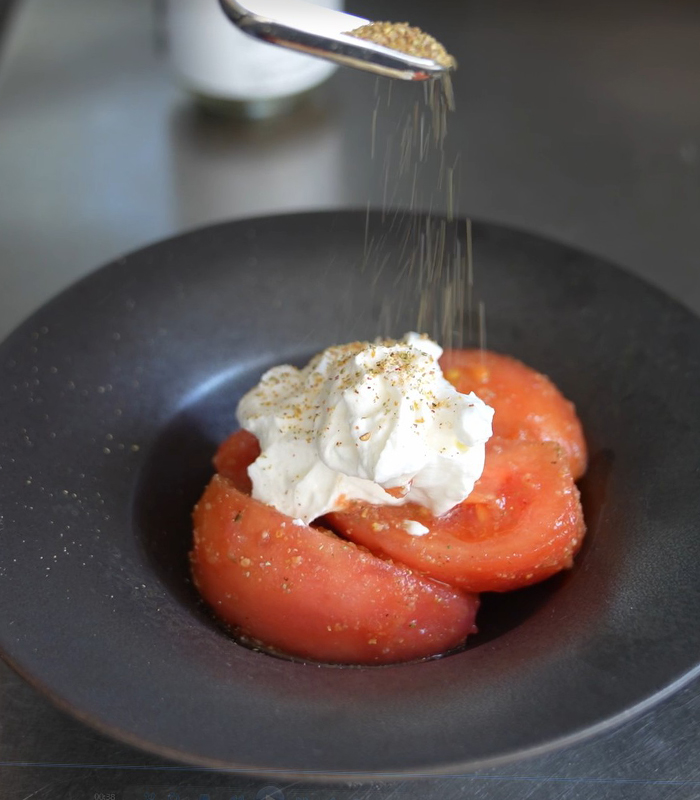 ハーブソルト「シトラスガーデンwithピンクソルト」の塩をトマトにかけている